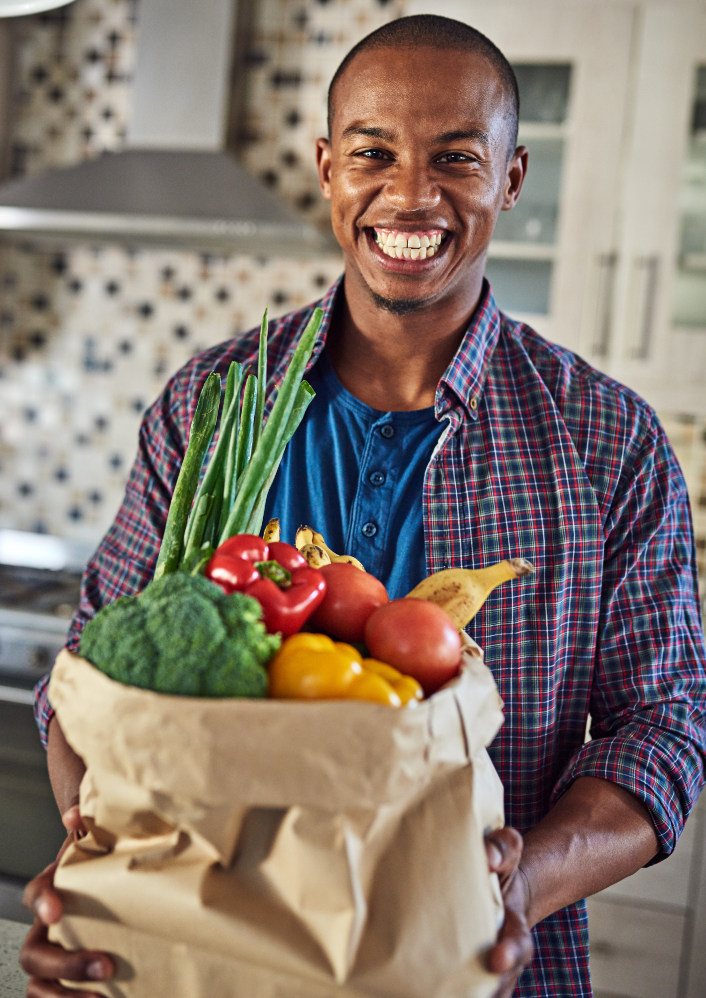 A black man holding a bag of vegetables