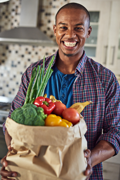 A black man holding a bag of vegetables